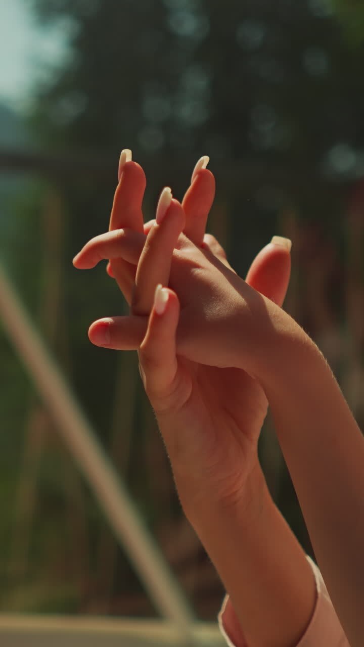 Intertwined fingers of mother and little daughter in morning sunlight. Family holds hands resting on lovely sunny day. Concept of loving mother taking care of tiny toddler