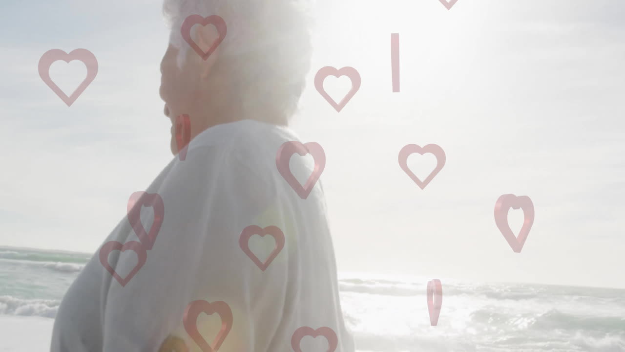 Walking on beach, senior person with animation of heart shapes overlaying scene