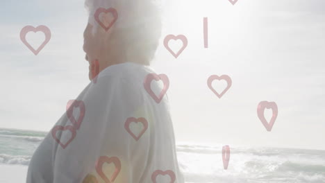 walking on beach, senior person with animation of heart shapes overlaying scene
