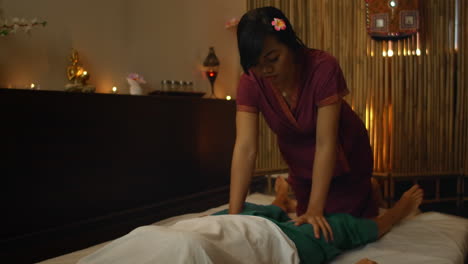 asian woman performs traditional thai massage to beautiful european woman. rehabilitation and treatment after injuries with the help of massage. relax and rest from massage of legs arms and back. therapeutic massage