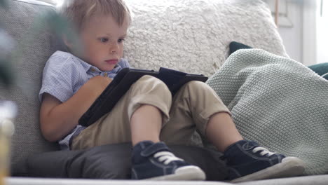 young boy learning new things on smartphone while sitting on couch