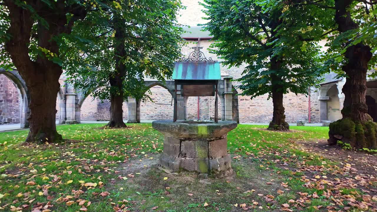 Old stone well in cloister garden of historic Notre-Dame-en-Saint-Melaine church, Rennes, France. First-person walking