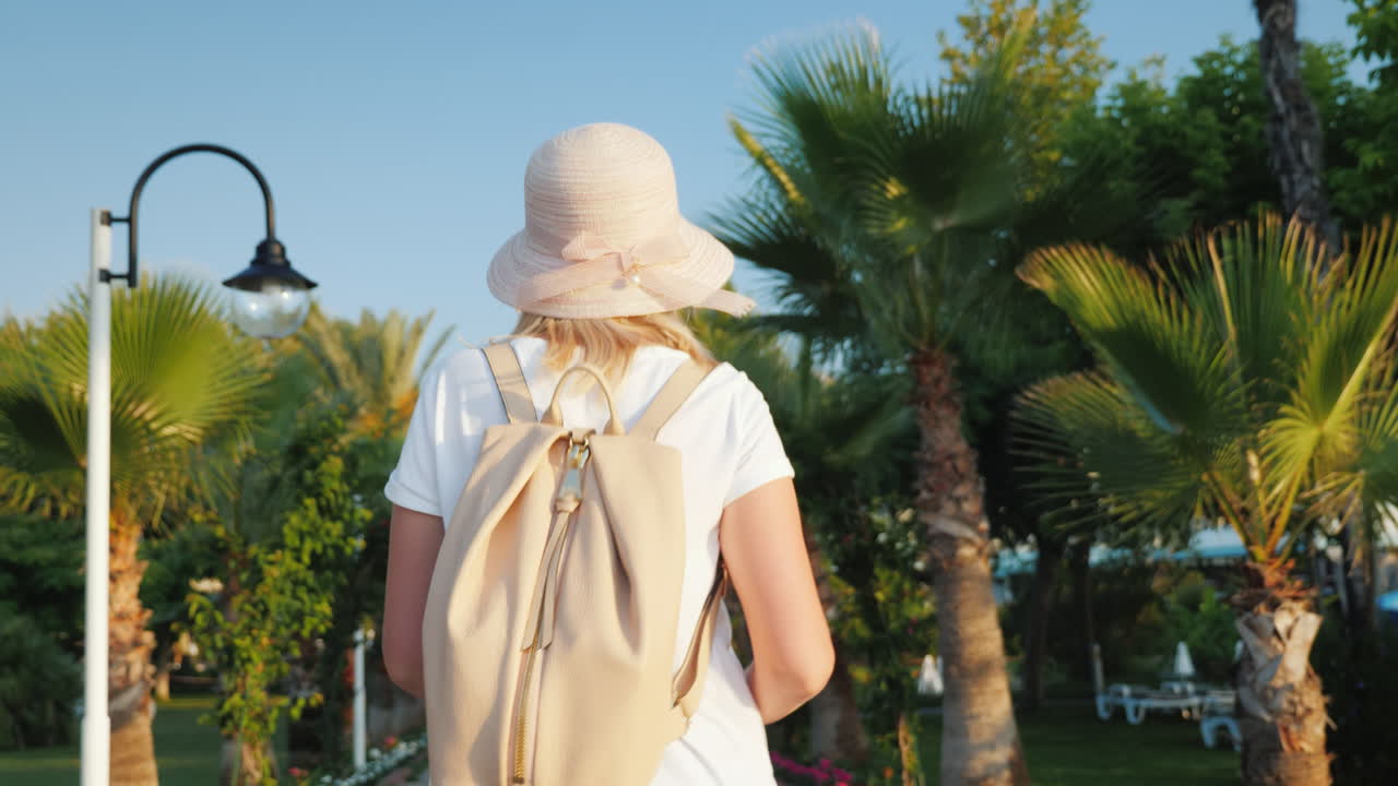 una turista con una mochila rosa a la espalda camina por la avenida de palmeras descansa y nuevo imp
