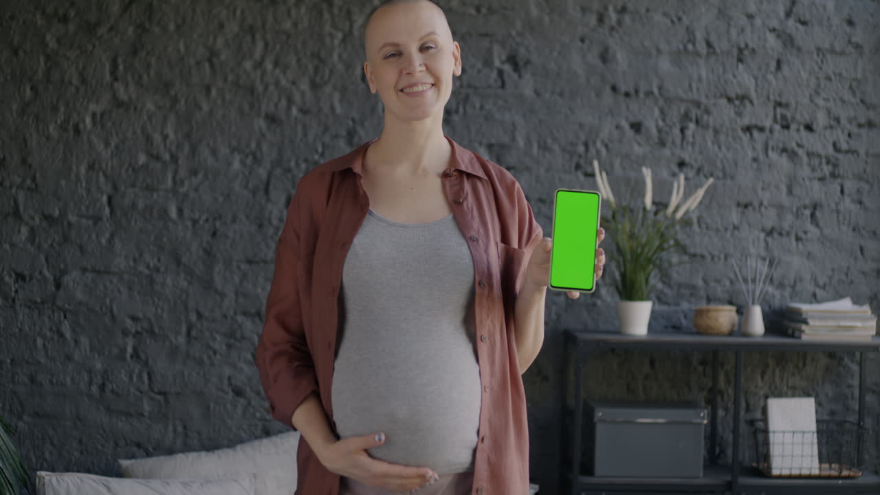 Mulher grávida segurando um smartphone com tela verde