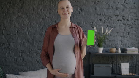 pregnant woman holding smartphone with green screen