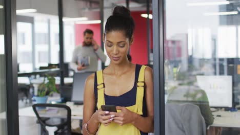 mujer de negocios de raza mixta usando un teléfono inteligente sonriendo a la cámara