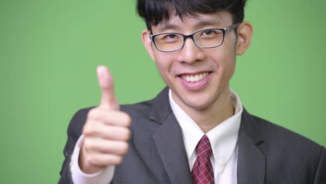 young happy asian businessman smiling while giving thumbs up to the camera