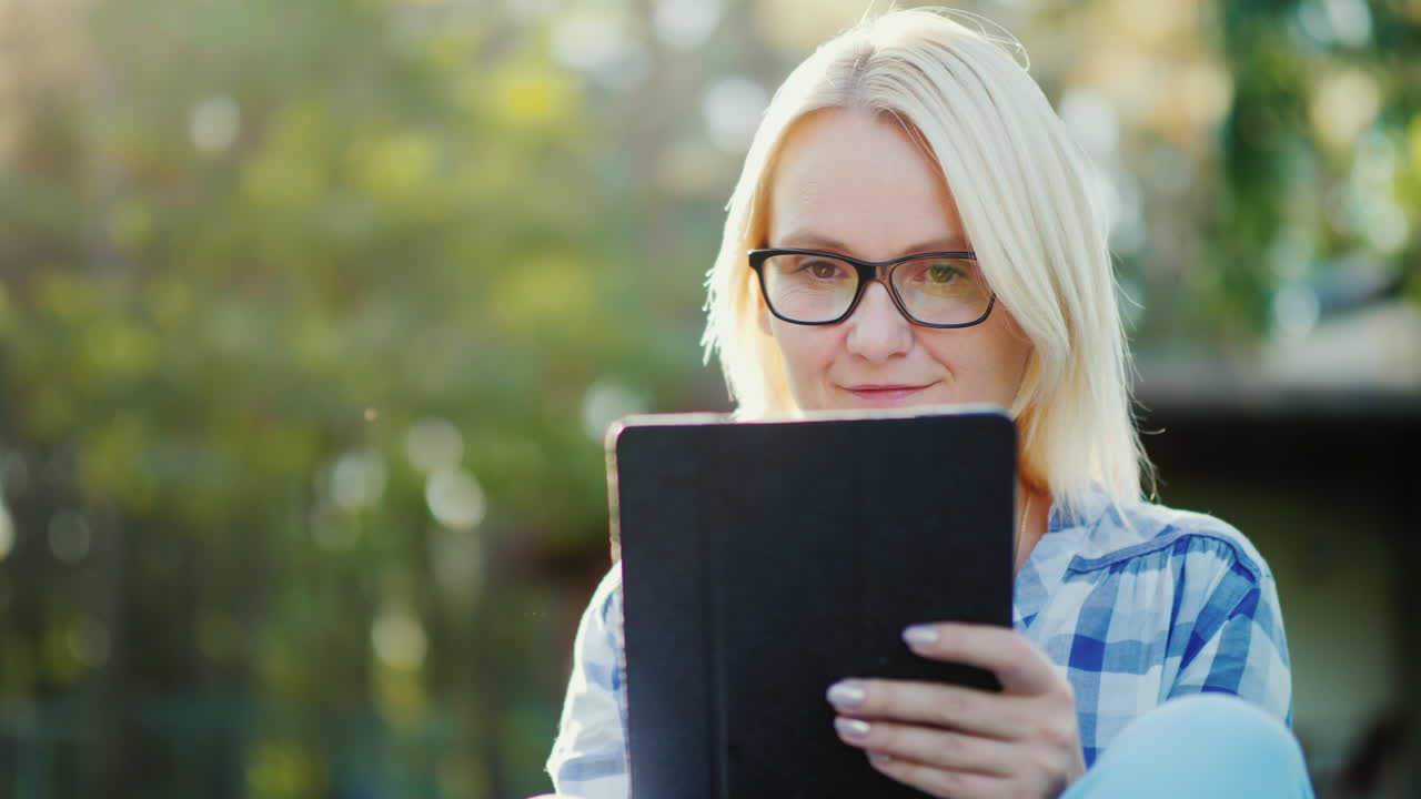 retrato de una mujer joven que disfruta de una tableta en el patio de su hogar concepto - tecnología y di