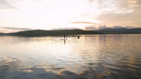 silhouette of people on standup paddleboard and kayak at sunrise on moso island in vanuatu