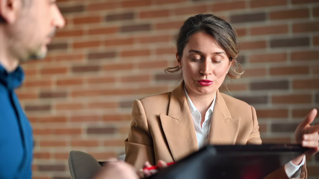 Man and woman discussing plans on a screen at the table, in an office
