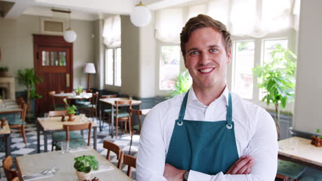 portrait of waiter standing in empty restaurant before start of service