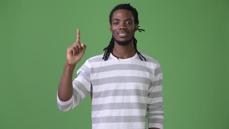joven hombre africano guapo con dreadlocks contra un fondo verde