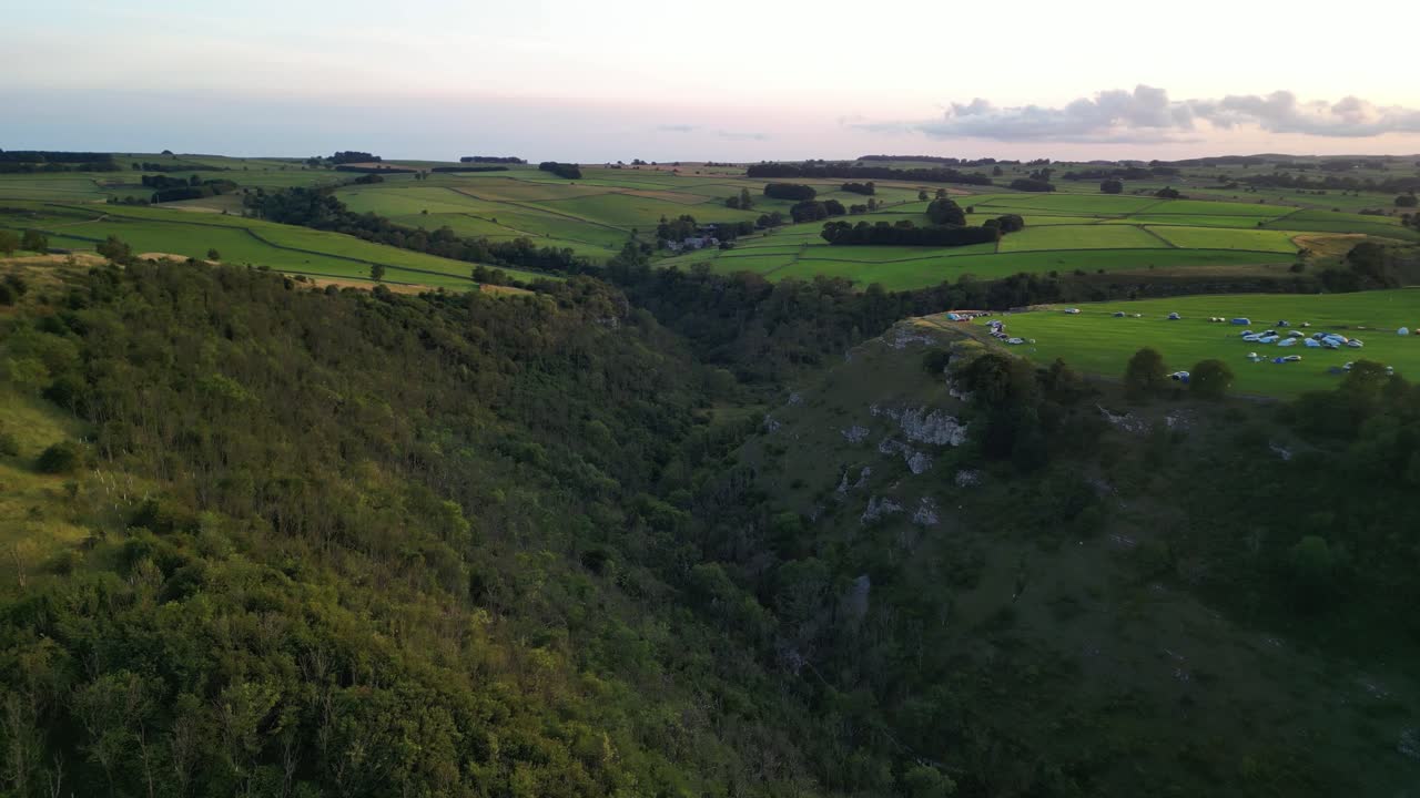 Beautiful Lathkill Dale - drone flies towards the golden sunset, The Peak District, Derbyshire, UK - valley middle