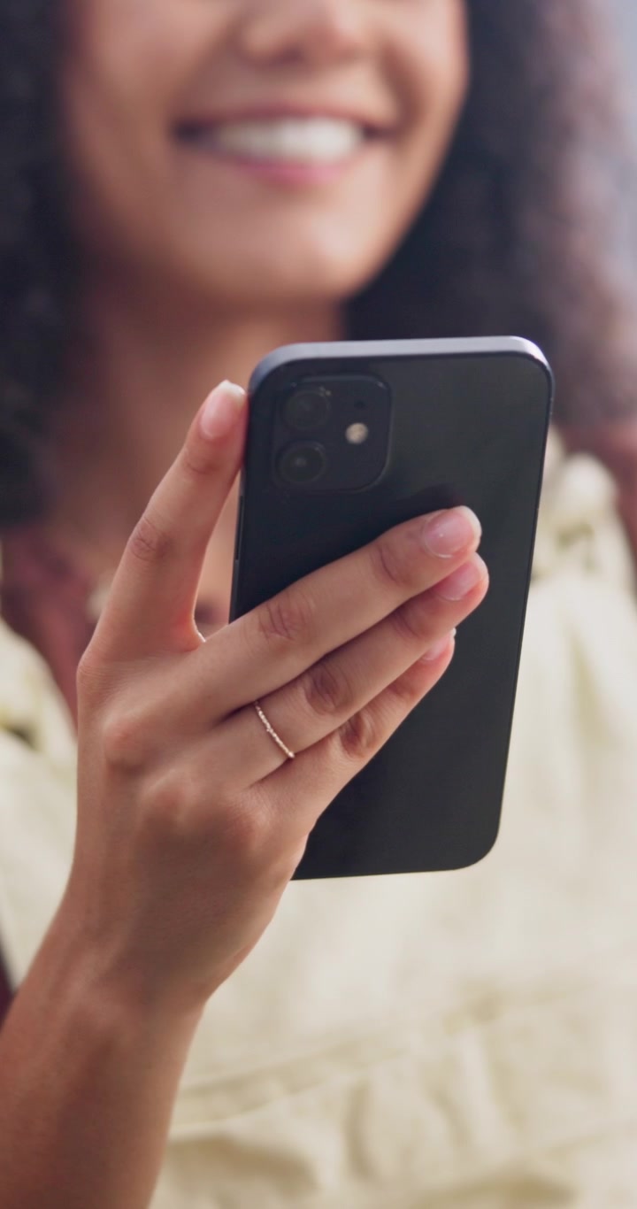 Donna sorridente che tiene in mano e guarda lo smartphone