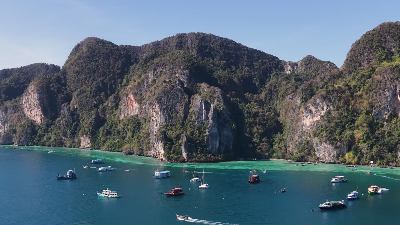 Cảnh quay từ máy bay không người lái ghi lại làn nước biển màu ngọc lam và những vách đá vôi với những chiếc thuyền neo đậu trong vịnh