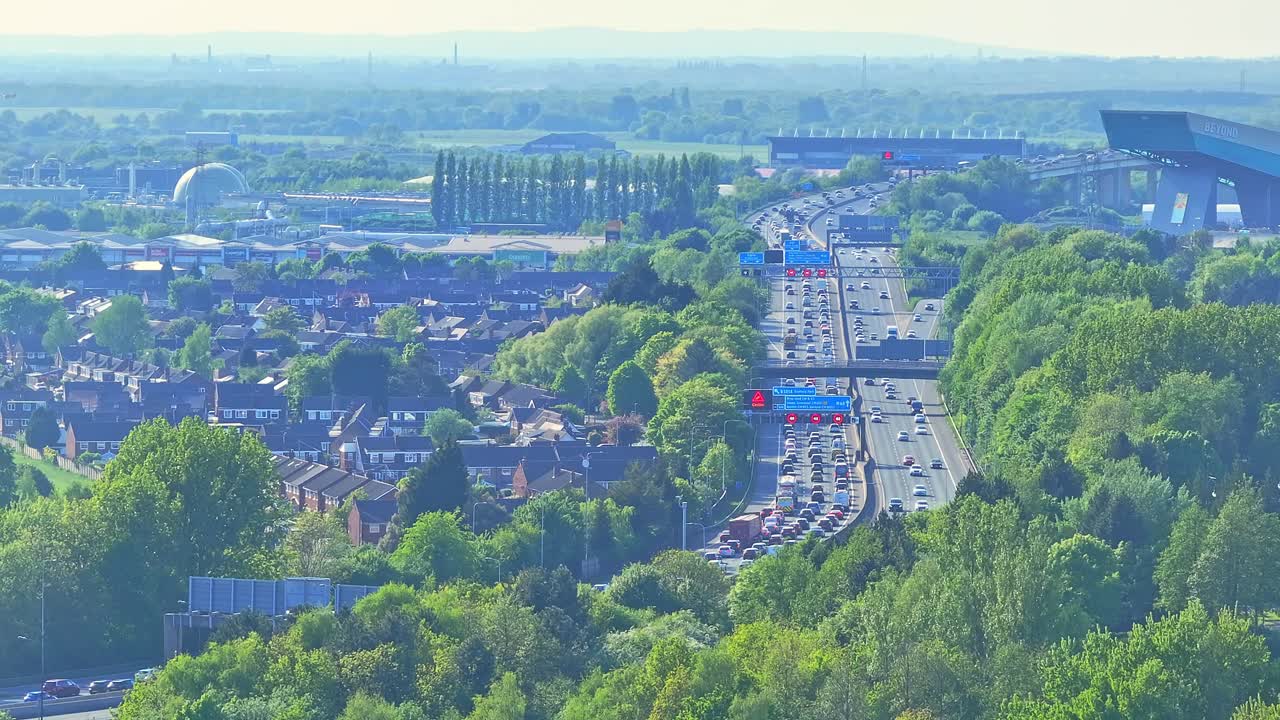 Busy highway with traffic near Trafford Centre large indoor shopping centre and entertainment complex in Trafford Park, Greater Manchester, England, crane up drone shot