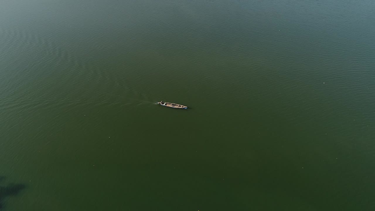 дронный кадр озера с одной лодкой, путешествующей