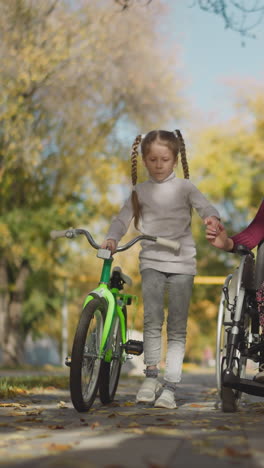 loving mom and little daughter with long braids walk in park. woman with spinal cord injury and preschooler hold hands tenderly and smile in joy of communication