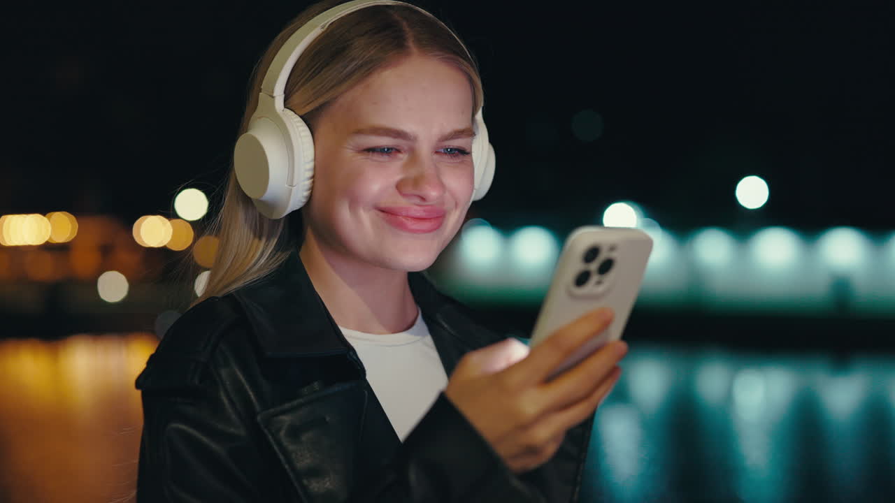 Woman listening to music on headphones while using smartphone at night