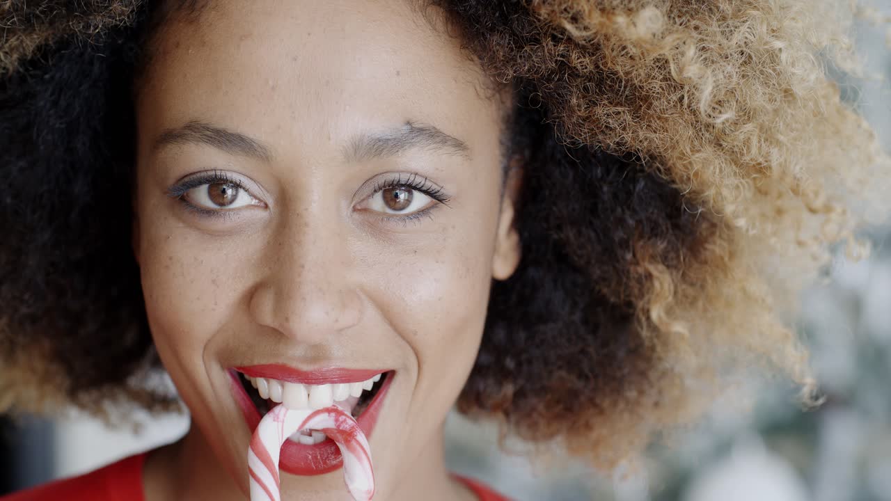 Fun young woman biting Christmas candy cane