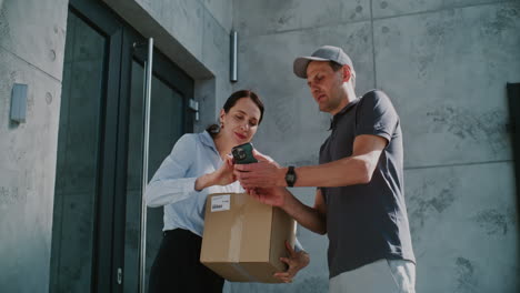 woman receiving a package from a delivery driver at a modern building entrance