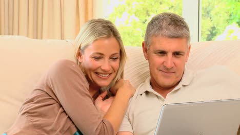 pareja divirtiéndose con su computadora portátil en el sofá