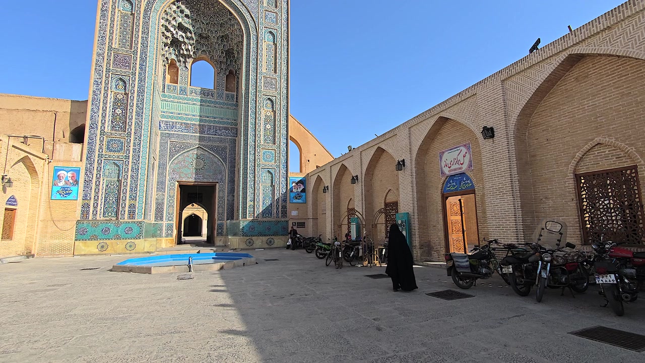 Donna in chador che cammina attraverso il cortile di una moschea storica