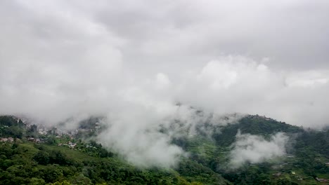 city nestled in mountain range with fast moving white cloud at morning from flat angle