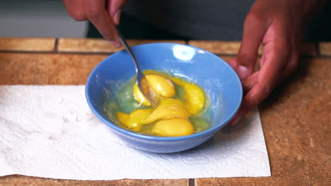 Scrambling-eggs-with-a-fork-in-a-bowl-for-breakfast---isolated-slow-motion