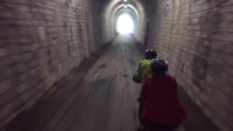 couple cycling through a stone tunnel