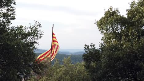 cámara lenta de la bandera catalana en la cima de una colina, con vistas a las colinas con un cielo nublado