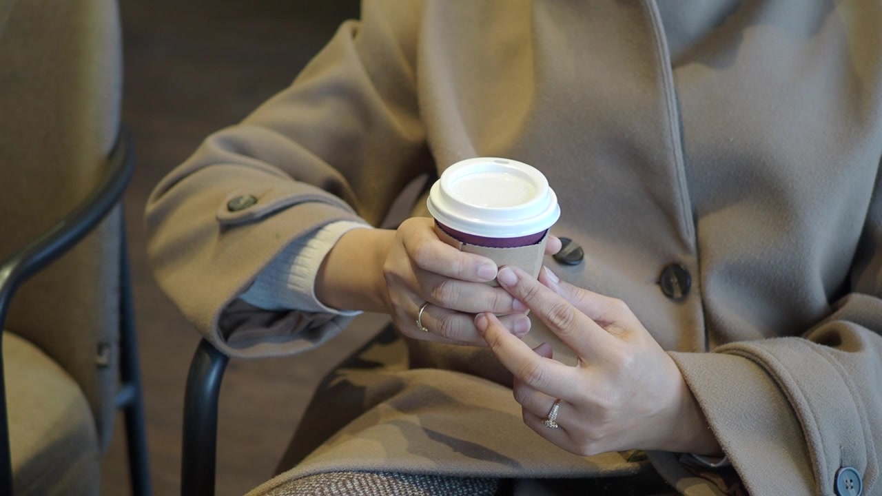 Donna che tiene una tazza di caffè usa e getta in un bar