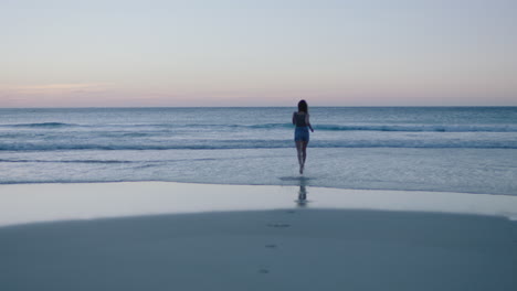 Mujer-Joven-Feliz-En-La-Playa-Corriendo-Hacia-Las-Olas-Del-Océano-Bailando-Emocionado-Chapoteando-Juguetón-Disfrutando-De-Un-Estilo-De-Vida-Relajado-Y-Despreocupado-En-Las-Vacaciones-De-Verano