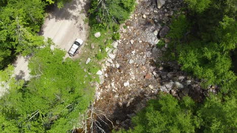 Fast-aerial-spin-above-dirt-road-and-river-in-Green-Mountains-Vermont