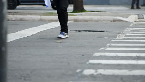 pedestrians crossing a street by the crosswalk of a big city in daylight filmed in slow motion in 4k high definition