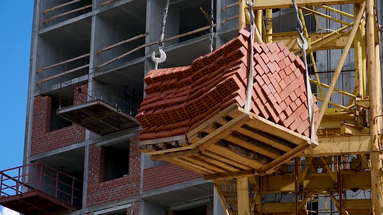 건설 현장에서 벽돌을 들어 올리는 크레인