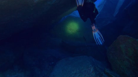 la persona si tuffa sott'acqua con la lampada che illumina la strada sopra le grandi rocce