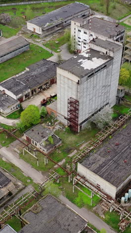 large territory of abandoned plant. damaged buildings of an old factory. ruined industry in springtime. aerial view. vertical video