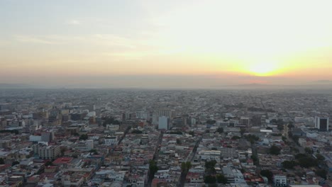 drone flies high above guadalajara city into beautiful sunset