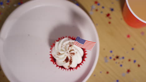 looking down on close up of cupcake with miniature american stars and stripes flag at party celebrating 4th july independence day