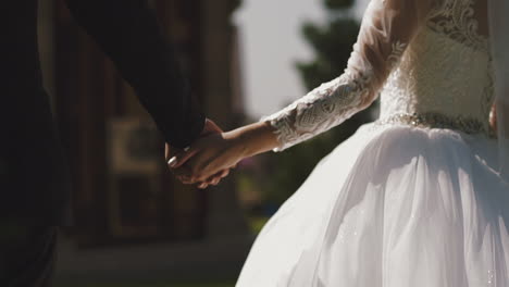 bride in gorgeous dress joins hands with groom on street