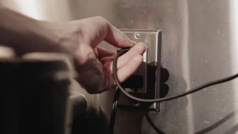 pulling out the electrical cord from the outlet to unplug the appliance - close up shot