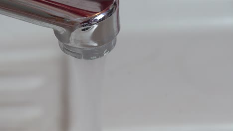 a man opens the water in a shiny chrome faucet, the water flows, then closes the water. macro. close up. low depth of field. scale and rust. mud. insanitary.
