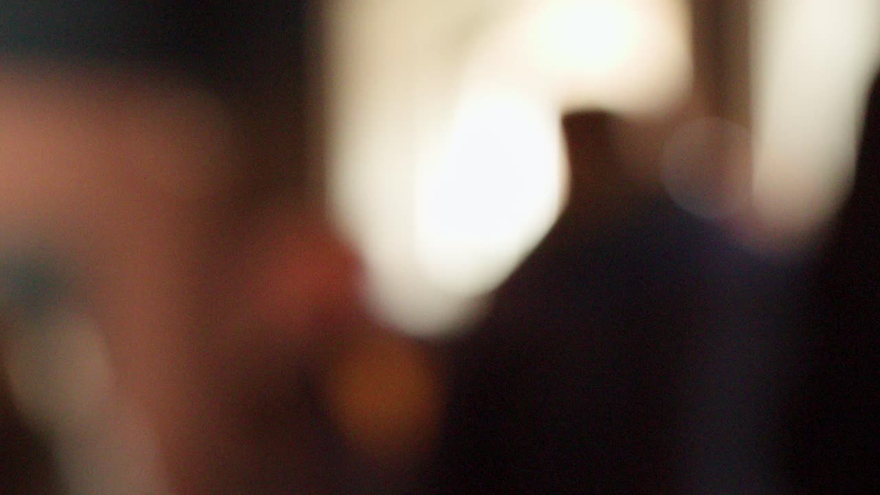 Blurry silhouettes of people indoors, soft bokeh lighting, warm tones, static camera, abstract mood