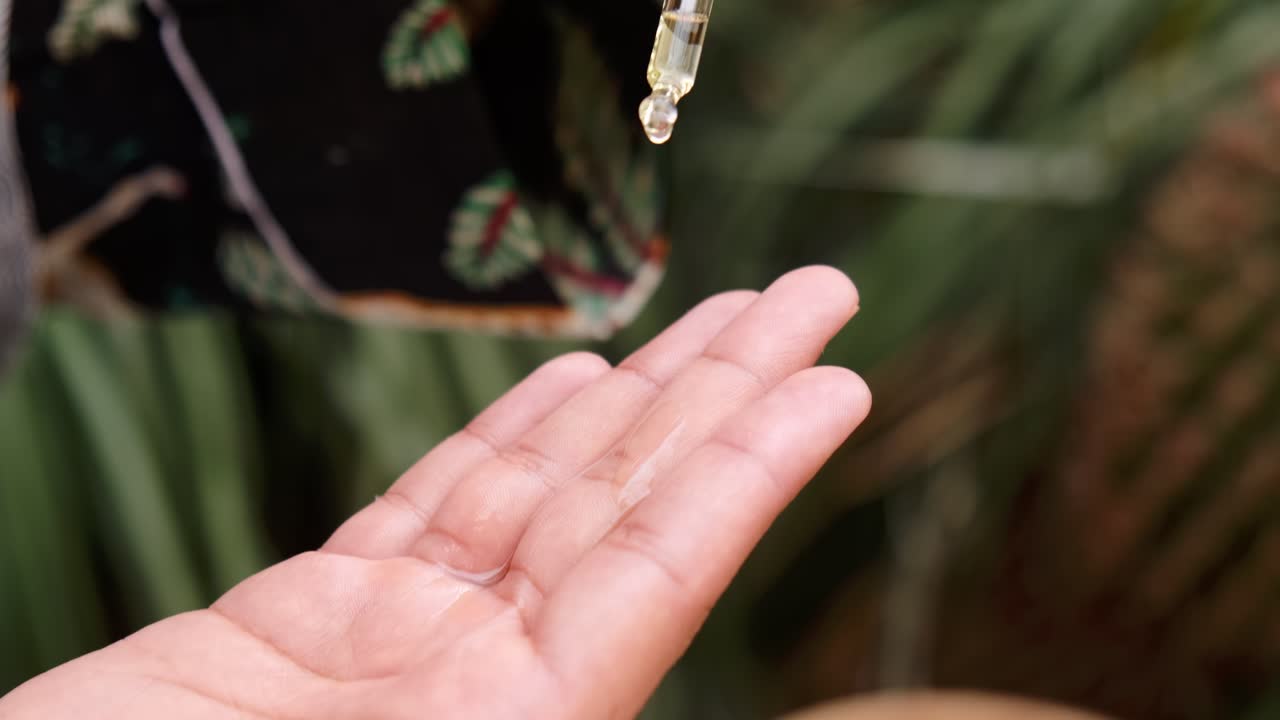 Natural oil dripping slow motion from pipette onto the palm of male hands. Organic cosmetics oil for hairm face and body.