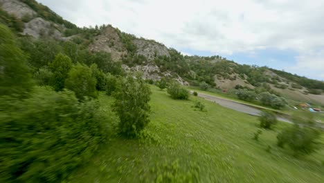 a small village near the river. the chain of mountains tower over a valley overgrown with diverse vegetation. lead-colored clouds in the sky. rural landscape.