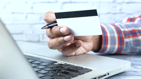 person holding a credit card over a laptop