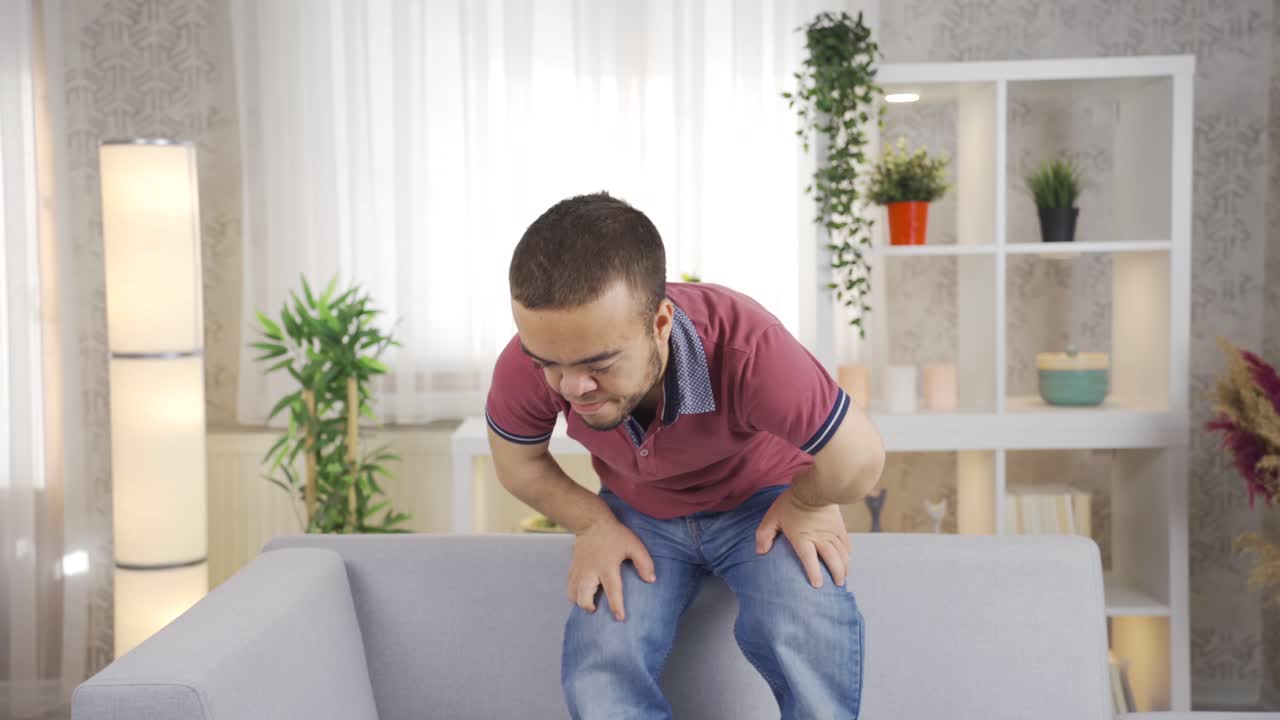 Young man with dwarfism sitting at home thoughtful and depressed.