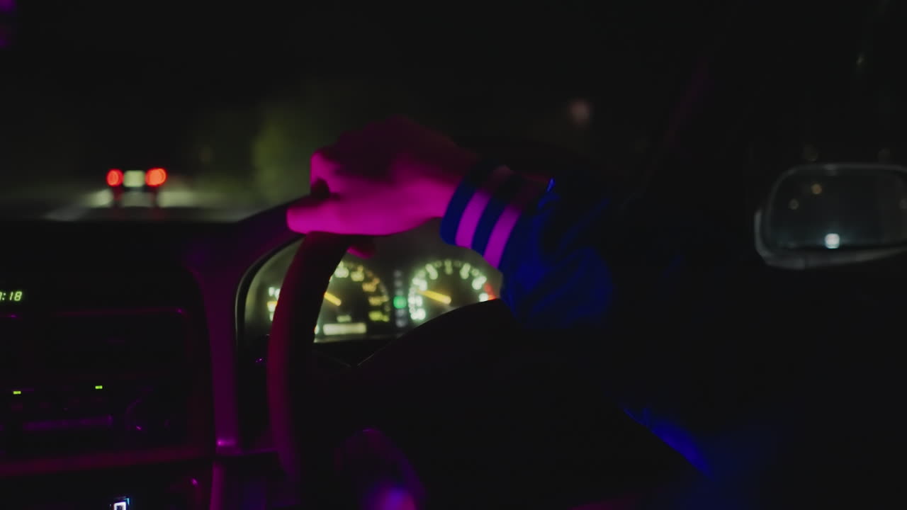 interior de coche de noche, conductor con la mano agarrando el volante, reflejos de neón en el salpicadero, velocímetro iluminado, luces traseras pasando en una carretera vacía, ambiente de mensajero nocturno, contemplativo