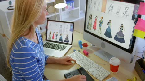 vista lateral de una diseñadora de moda caucásica usando una tableta gráfica en el escritorio en la oficina 4k
